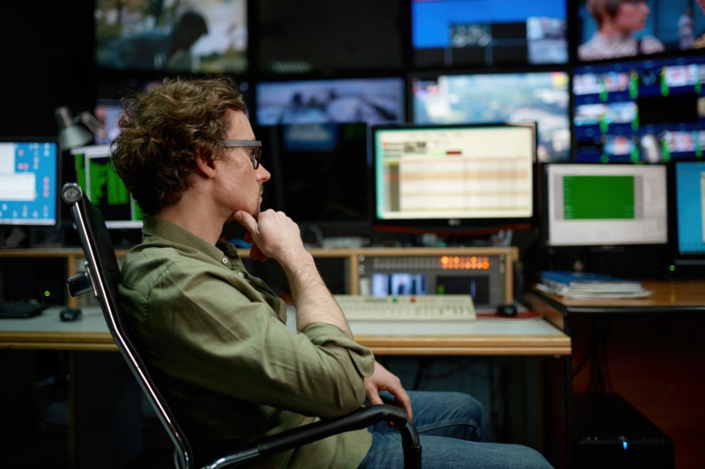 System administrator sitting in chair looking at computer screen in server room