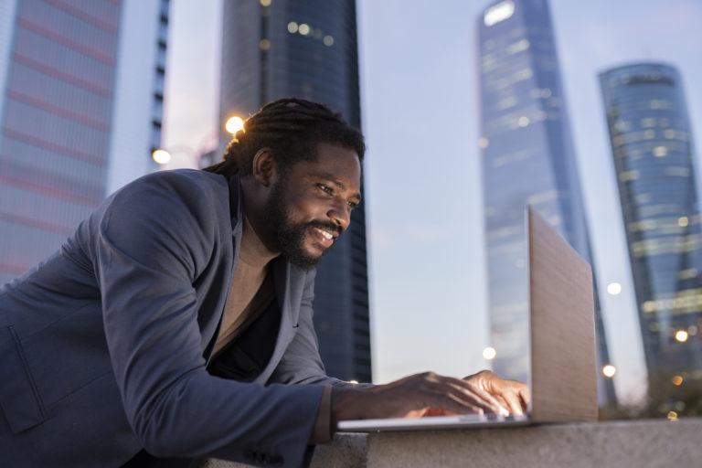 handsome afro american businessman using computer at night in city buildings