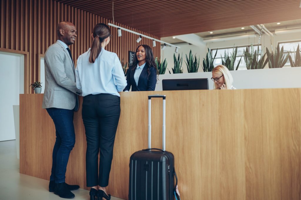 Two smiling guests checking in at a hotel reception